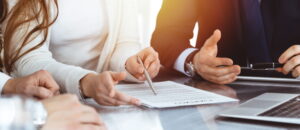 Unknown businessman and woman with colleagues or lawyers at meeting.